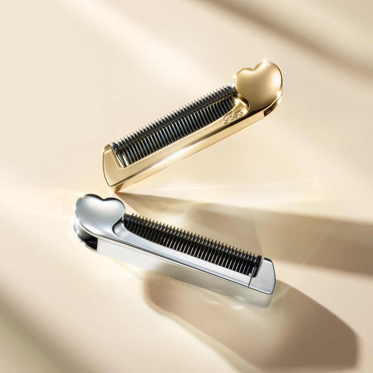 ReFa HEART COMB IRON Aira in gold and silver, crossed on a warm gold backdrop