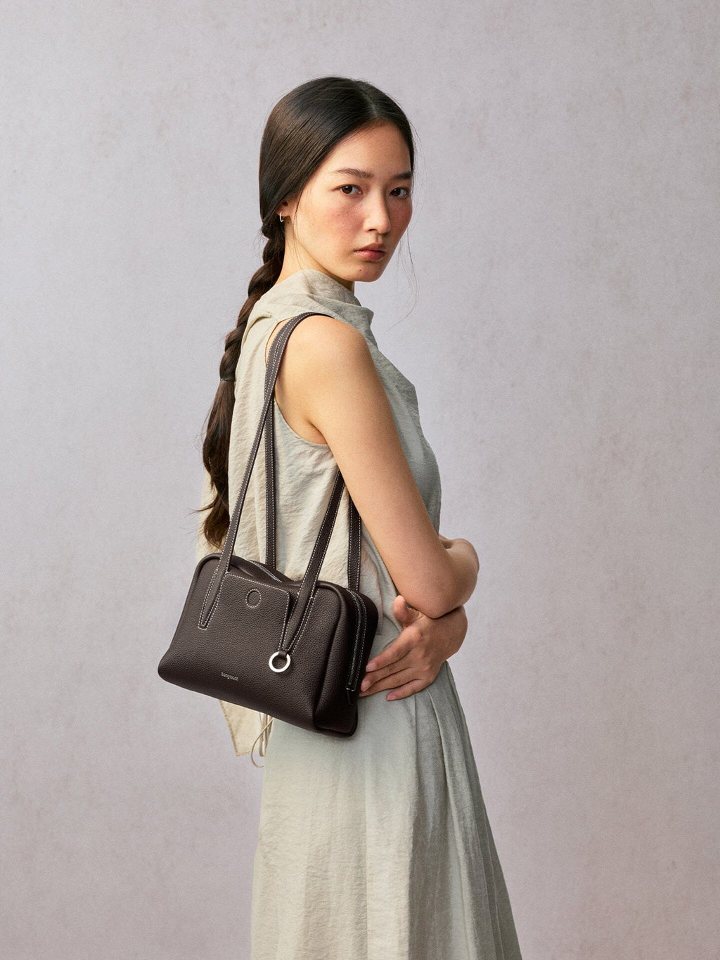 Songmont Small Yore Trunk Bag Dark Brown - worn on the shoulder with arms crossed
