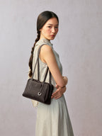 Songmont Small Yore Trunk Bag Dark Brown - worn on the shoulder with arms crossed