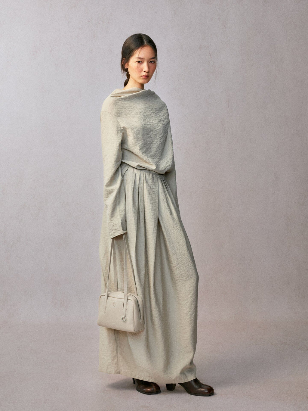 Songmont Small Yore Trunk Bag Cloud - carried by hand at the side in a long pale dress