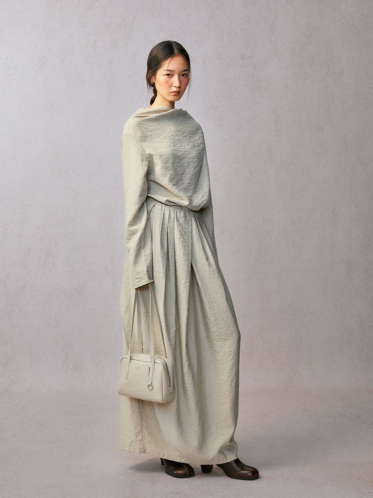 Songmont Small Yore Trunk Bag Cloud - carried by hand at the side in a long pale dress