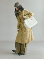 Songmont Large Yore Tote Bag Cloud - worn on the arm while walking in a trench coat