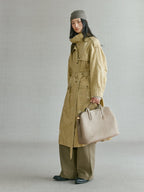 Songmont Large Yore Tote Bag Cobble - carried by the top handle with an olive trench coat