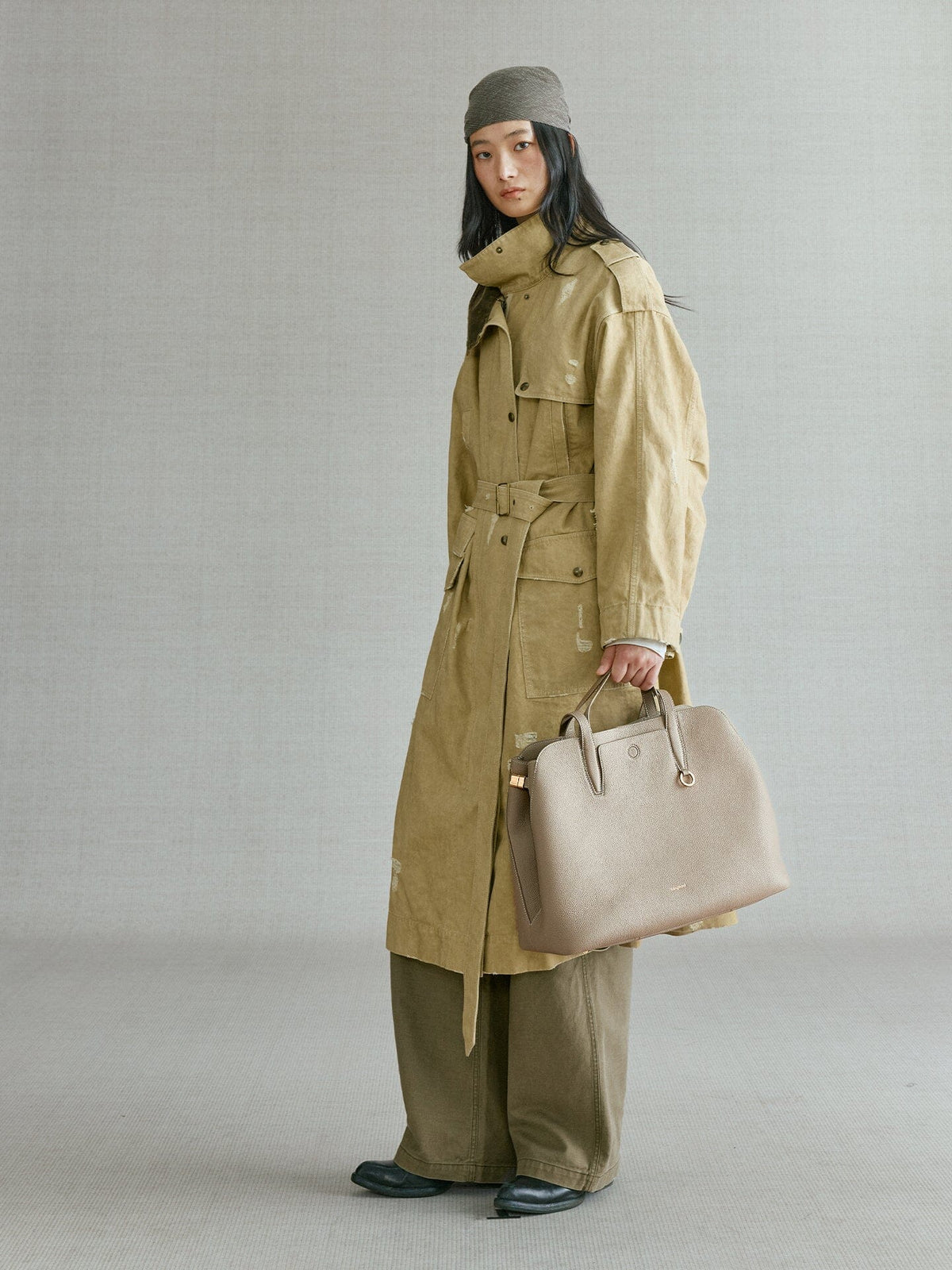 Songmont Large Yore Tote Bag Cobble - carried by the top handle with an olive trench coat
