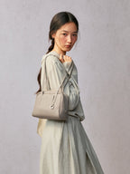 Songmont Small Yore Trunk Bag Smoke Grey - worn on the shoulder with a hand on the strap