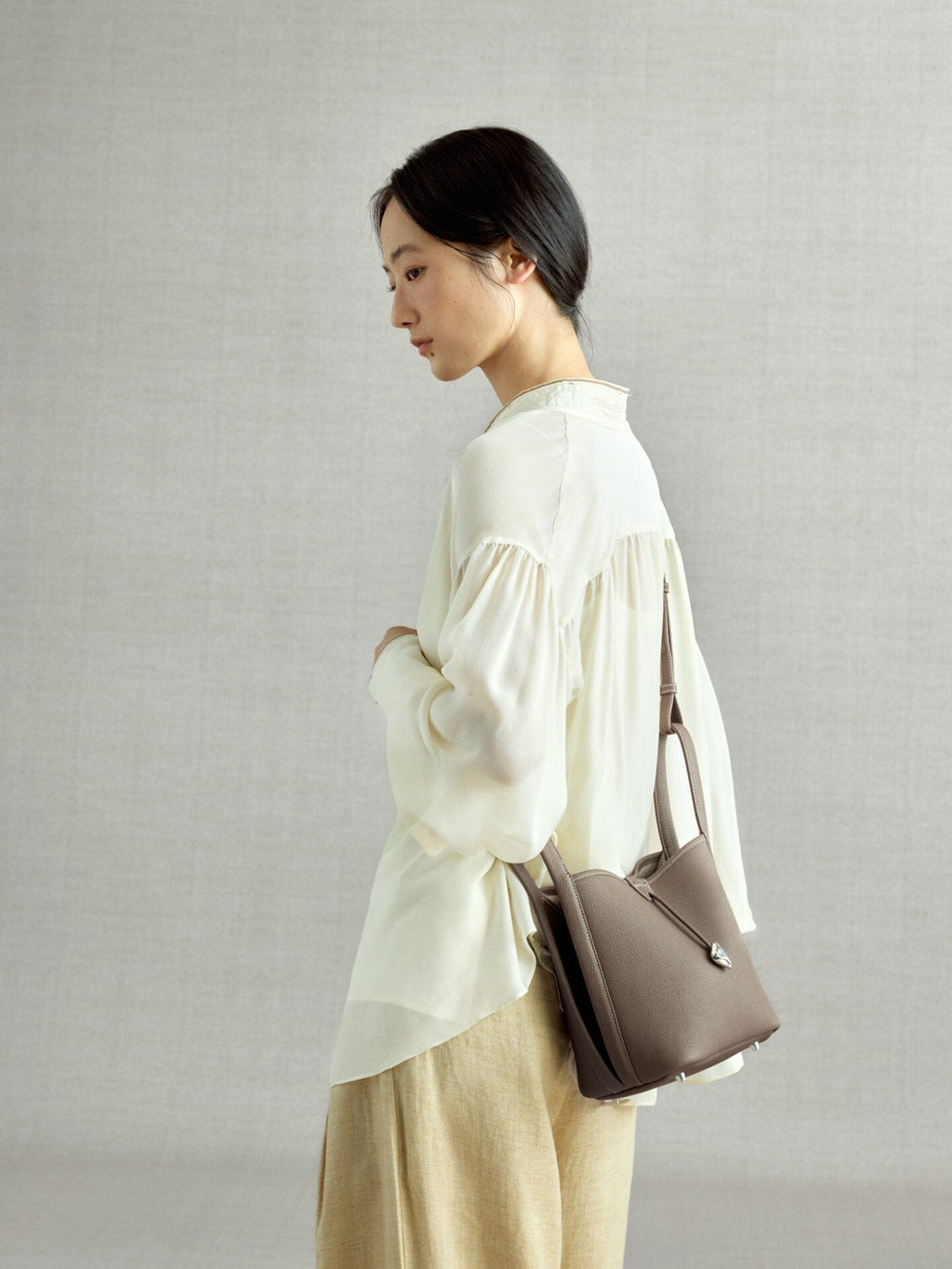 Songmont Song Bucket Bag Taupe - worn cross-body, side view