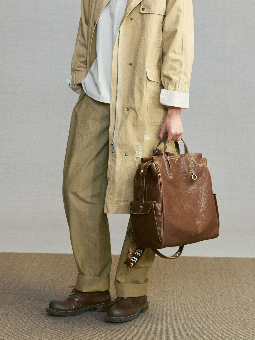 Songmont Large Yore Backpack Sandal - carried by hand with a khaki coat