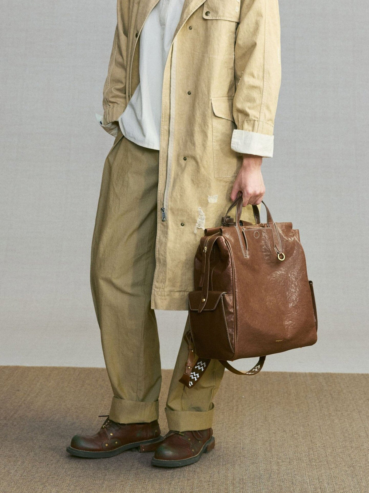 Songmont Large Yore Backpack Sandal - carried by hand with a khaki coat