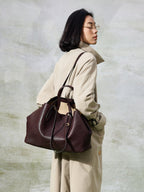 Songmont Large Yore Tote Bag Raisin - worn on the shoulder with a trench coat