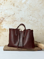 Songmont Large Yore Tote Bag Raisin - open tote shape on a wooden block