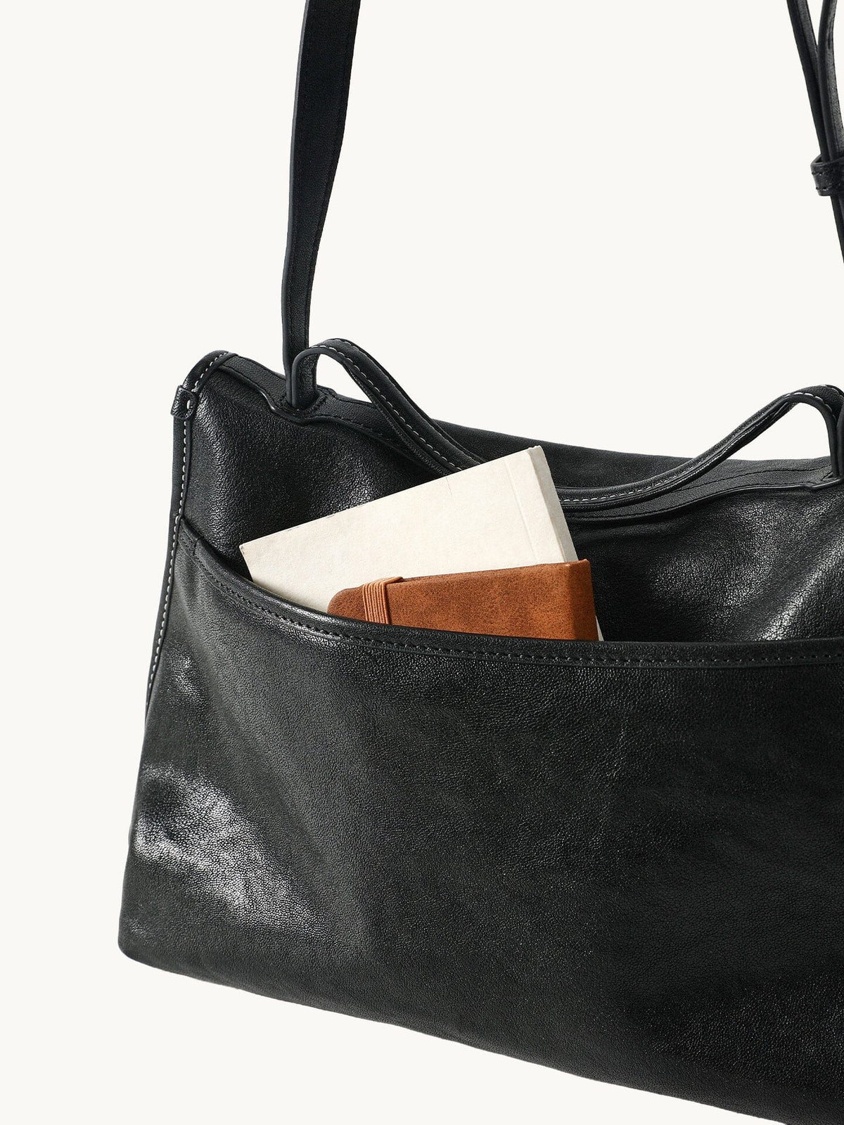 Songmont Small Shan Messenger Bag Onyx - hanging by the strap with a notebook in the pocket