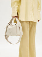 Songmont Drippy Roof Bag Ivory - carried by hand with the strap hanging
