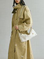 Songmont H Yore Bag Cloud - carried in hand with a khaki trench coat