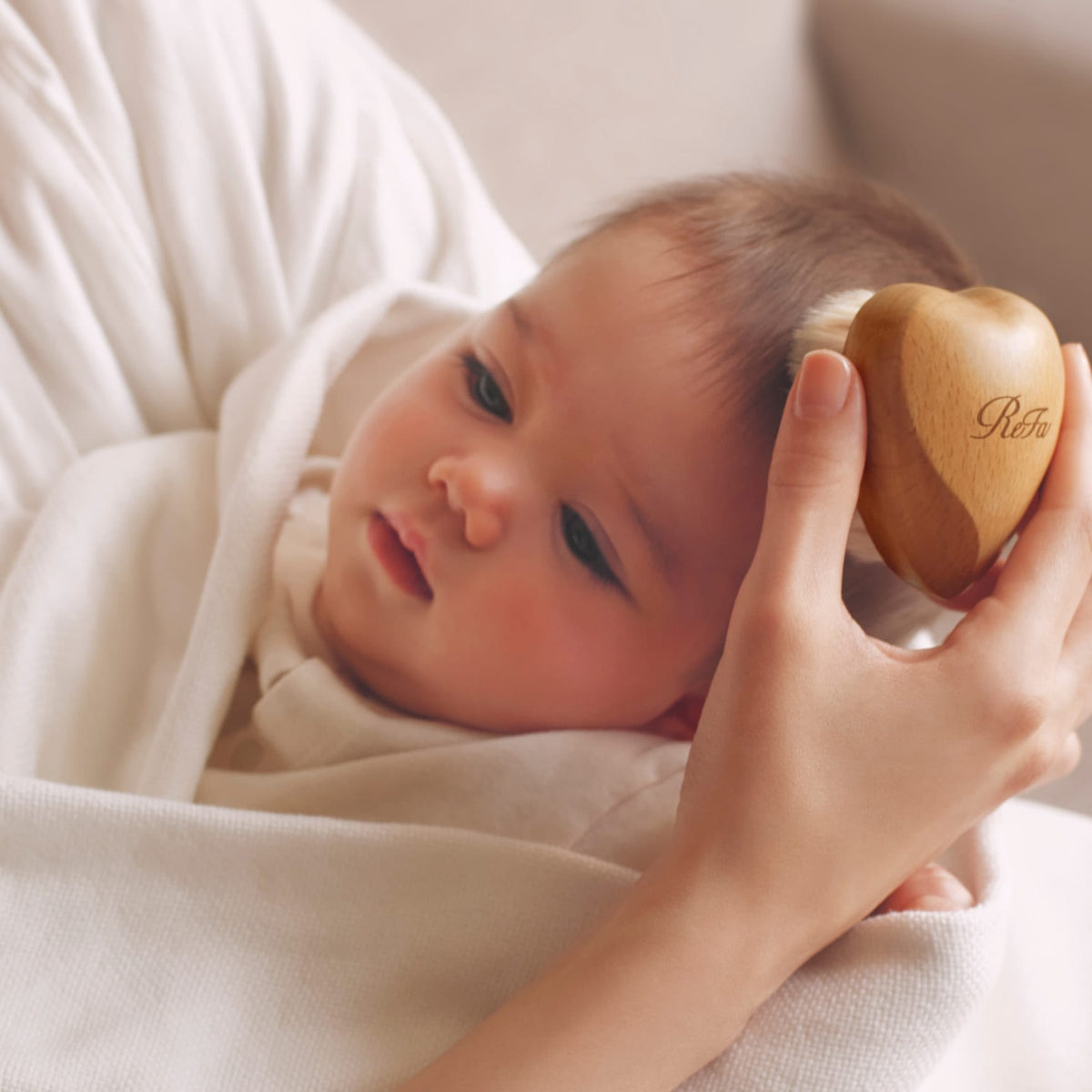 ReFa BABY SLEEPY Heart brush held at baby's head