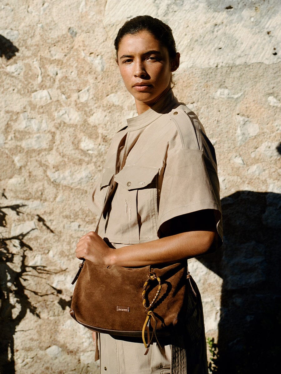 Songmont Large Yore Hobo Bag Sandal Suede - model holding the bag against a stone wall
