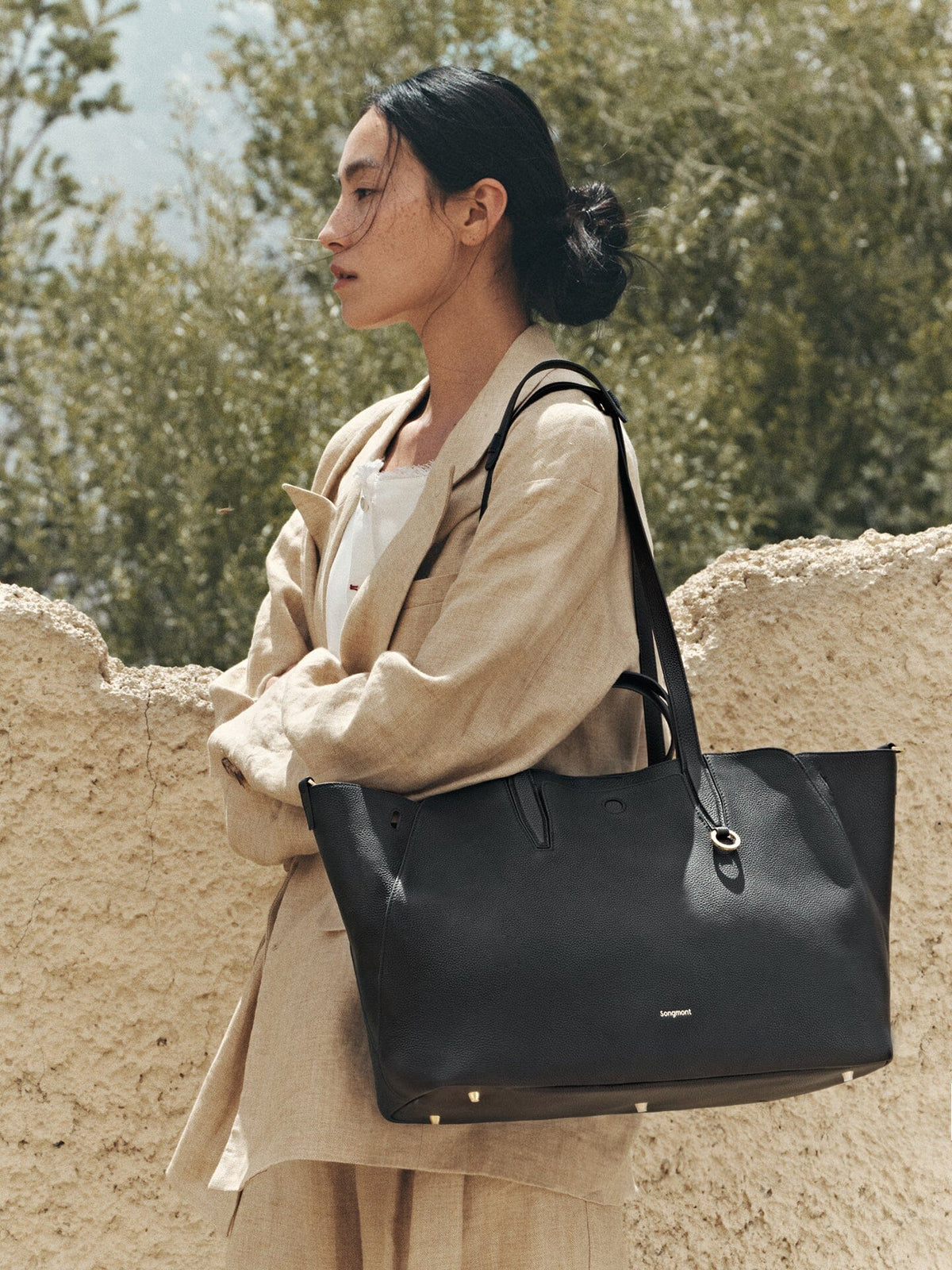 Songmont Large Yore Tote Bag Onyx - carried on the shoulder with a linen coat