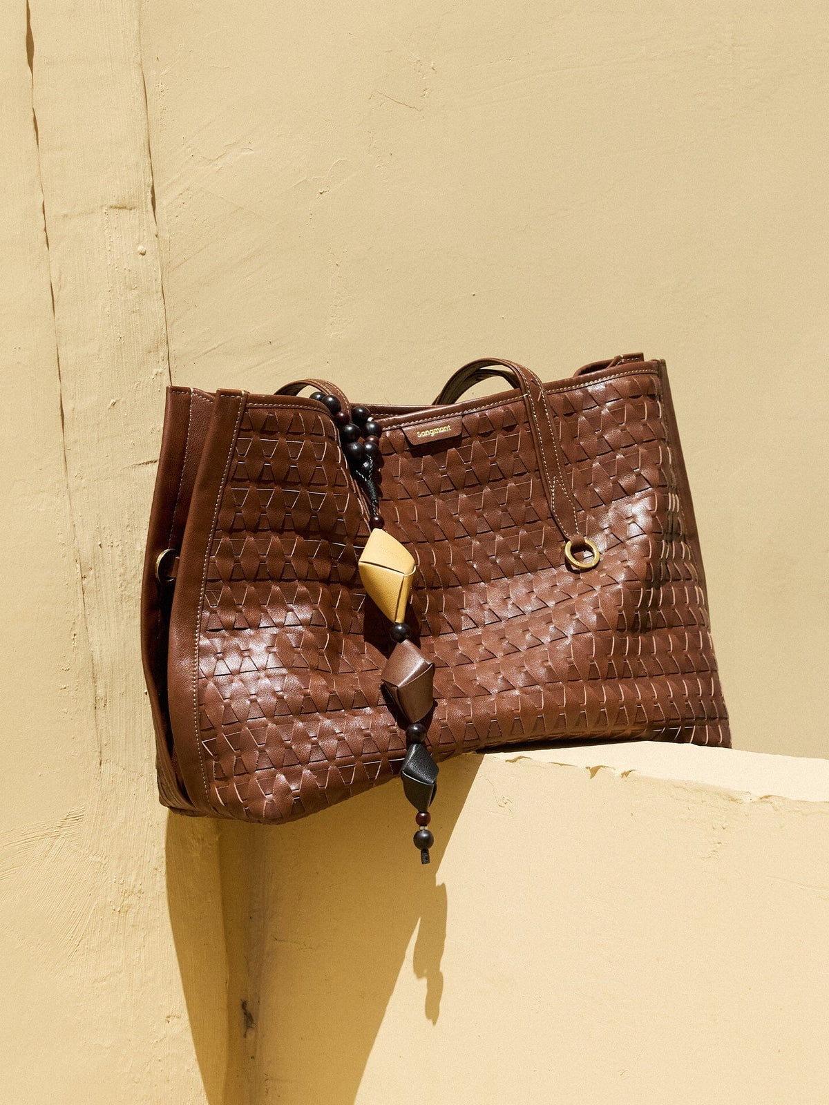 Songmont Medium Lattice Tote Sandal - styled against a yellow wall