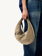 Songmont Large Luna Hobo Bag Dune Suede - carried by hand beside denim