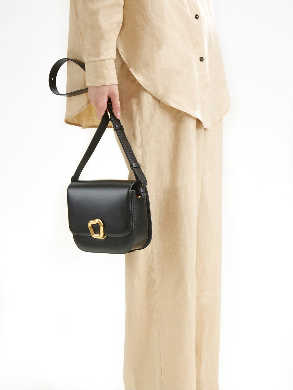 Songmont Medium Reset Tofu Bag Onyx - held by the strap against a linen outfit