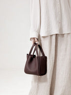 Songmont Medium Song Bag Burgundy carried by the top handles