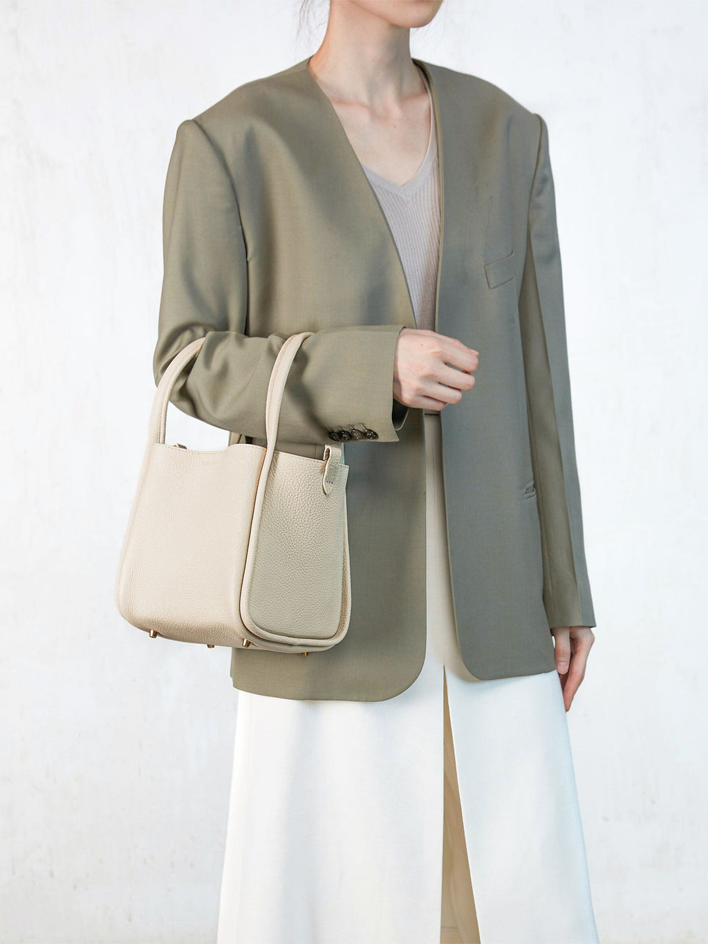 Songmont Medium Song Bag Ivory carried on the arm with a tailored blazer