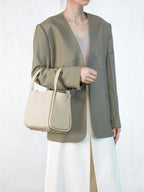 Songmont Medium Song Bag Ivory carried on the arm with a tailored blazer