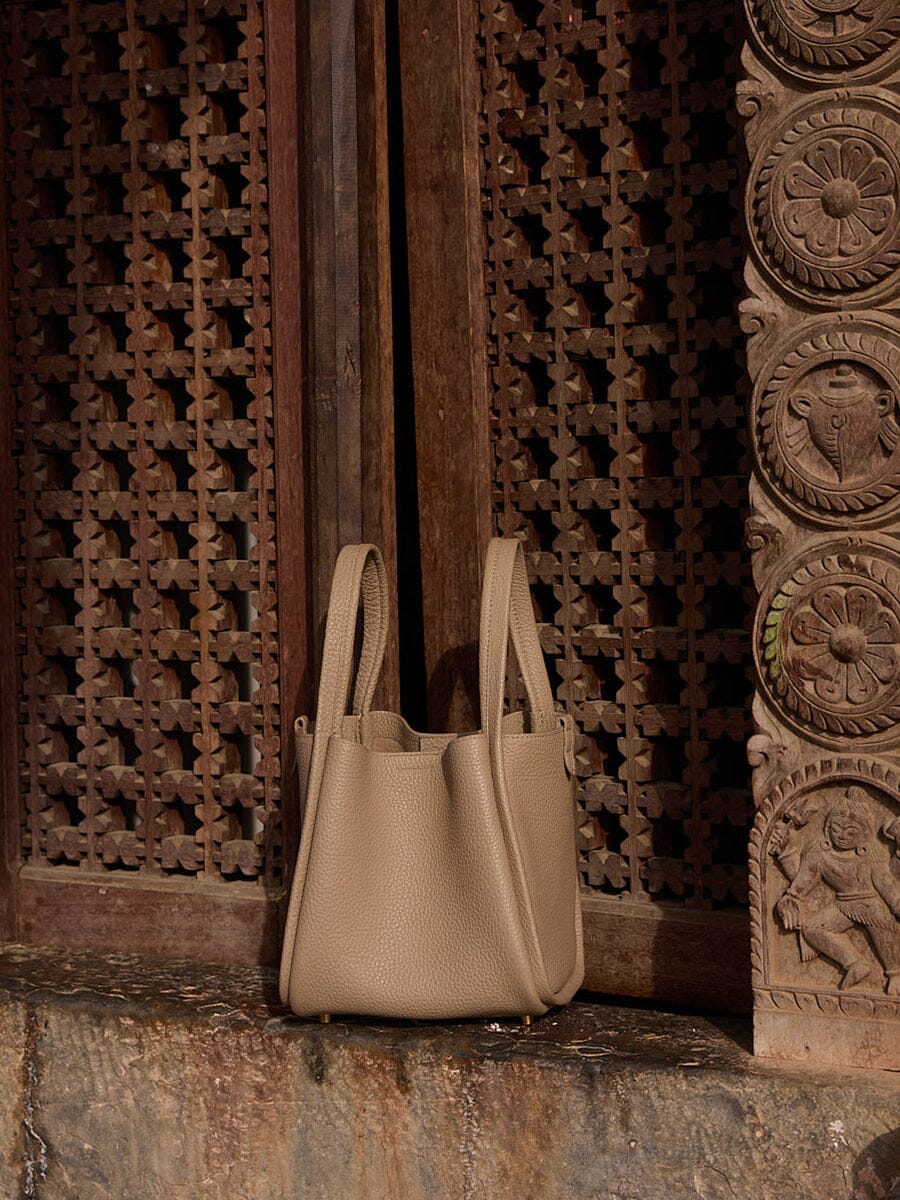 Songmont Medium Song Bag Taupe in a carved wooden doorway