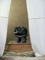 Songmont Medium Yore Duffle Bag Onyx - styled on a carved wooden stool
