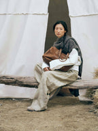 Songmont Medium Yore Duffle Bag Sandal - held on the lap by a seated model