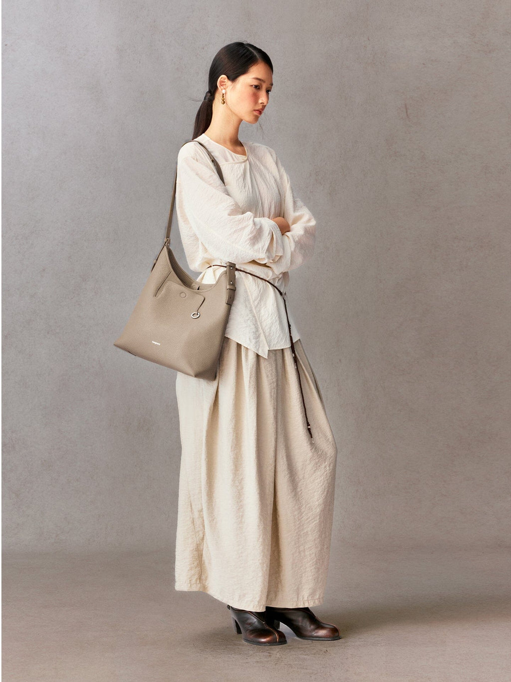 Songmont Medium Yore Shoulder Bag Smoke Grey - worn over the shoulder with a cream blouse