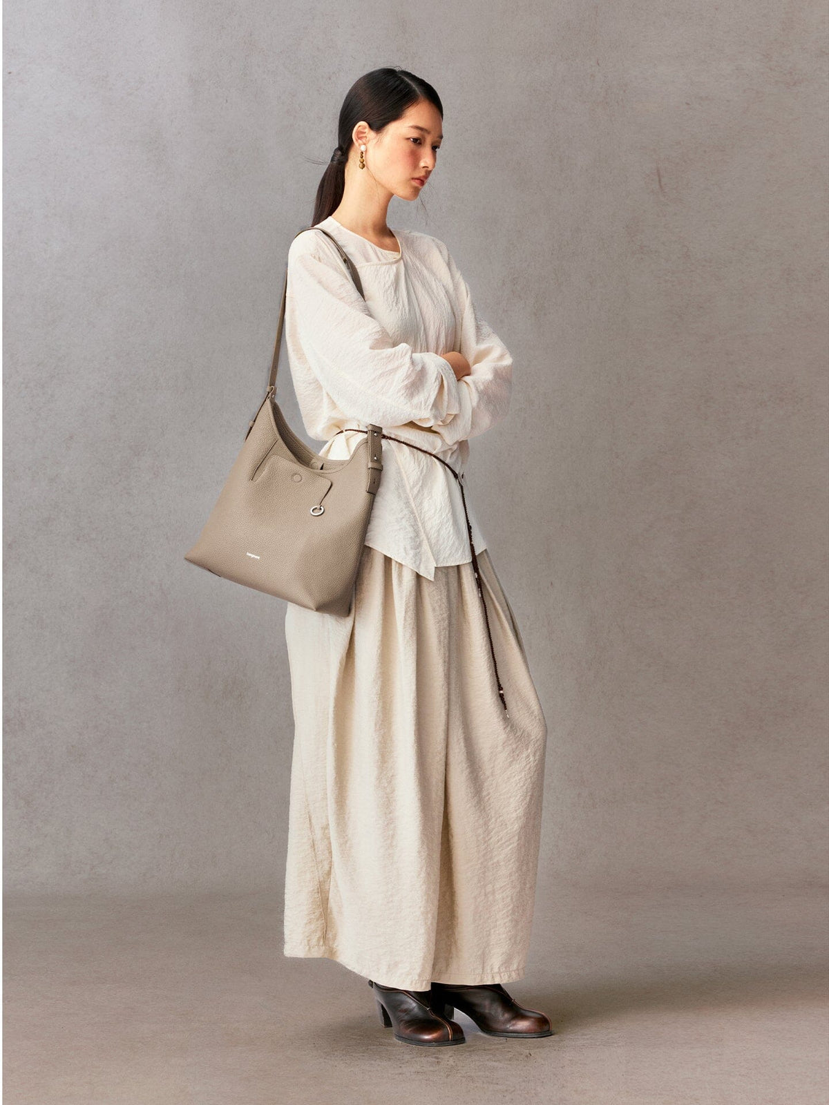 Songmont Medium Yore Shoulder Bag Smoke Grey - worn over the shoulder with a cream blouse