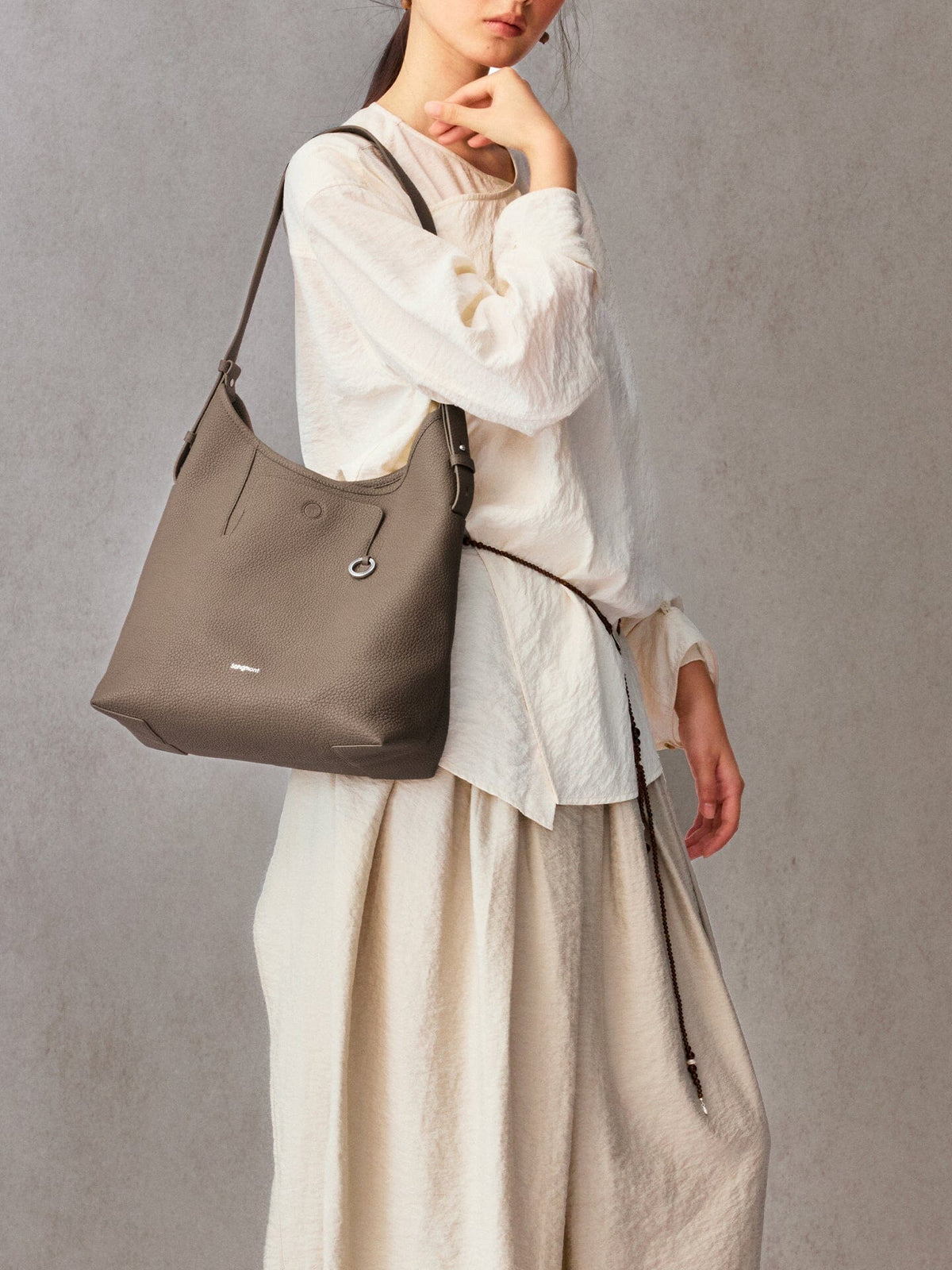 Songmont Medium Yore Shoulder Bag Stone - worn over the shoulder with a cream blouse