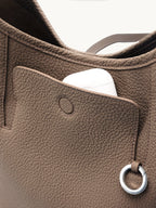 Songmont Medium Yore Shoulder Bag Stone - front pocket open with an AirPods case inside