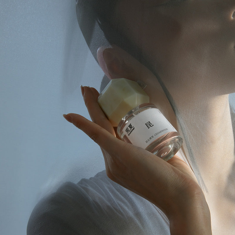 TO SUMMER Cedarwood Eau de Parfum held beside the ear