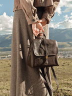 Songmont Mini Shan Backpack Drab - carried by the top handle outdoors