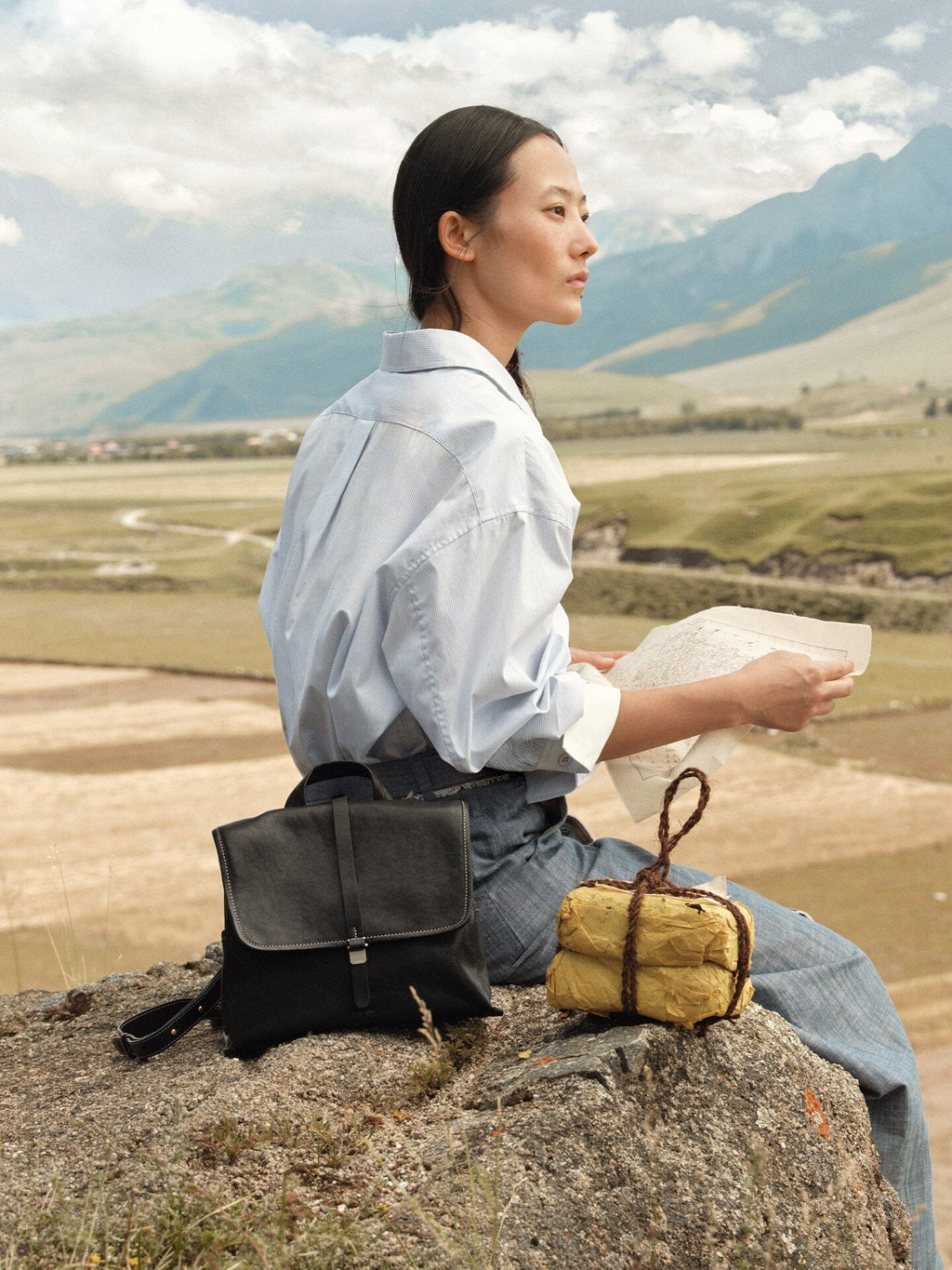 Songmont Mini Shan Backpack Onyx - styled on a rock in a mountain landscape
