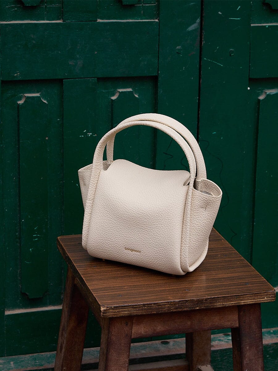 Songmont Mini Song Bag Ivory - styled on a wooden stool