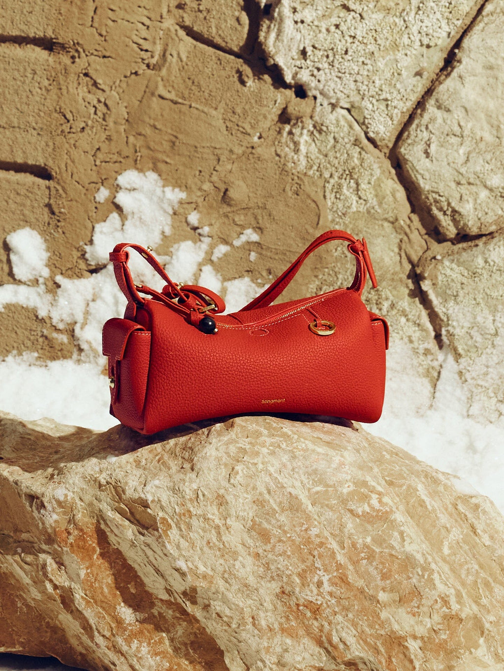 Songmont Mini Yore Camera Bag Lucky Red - red bag resting on a sunlit rock