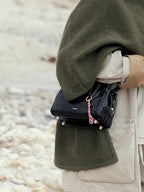 Songmont Mini Yore Duffle Bag Onyx - at the hip with a red and white cord charm