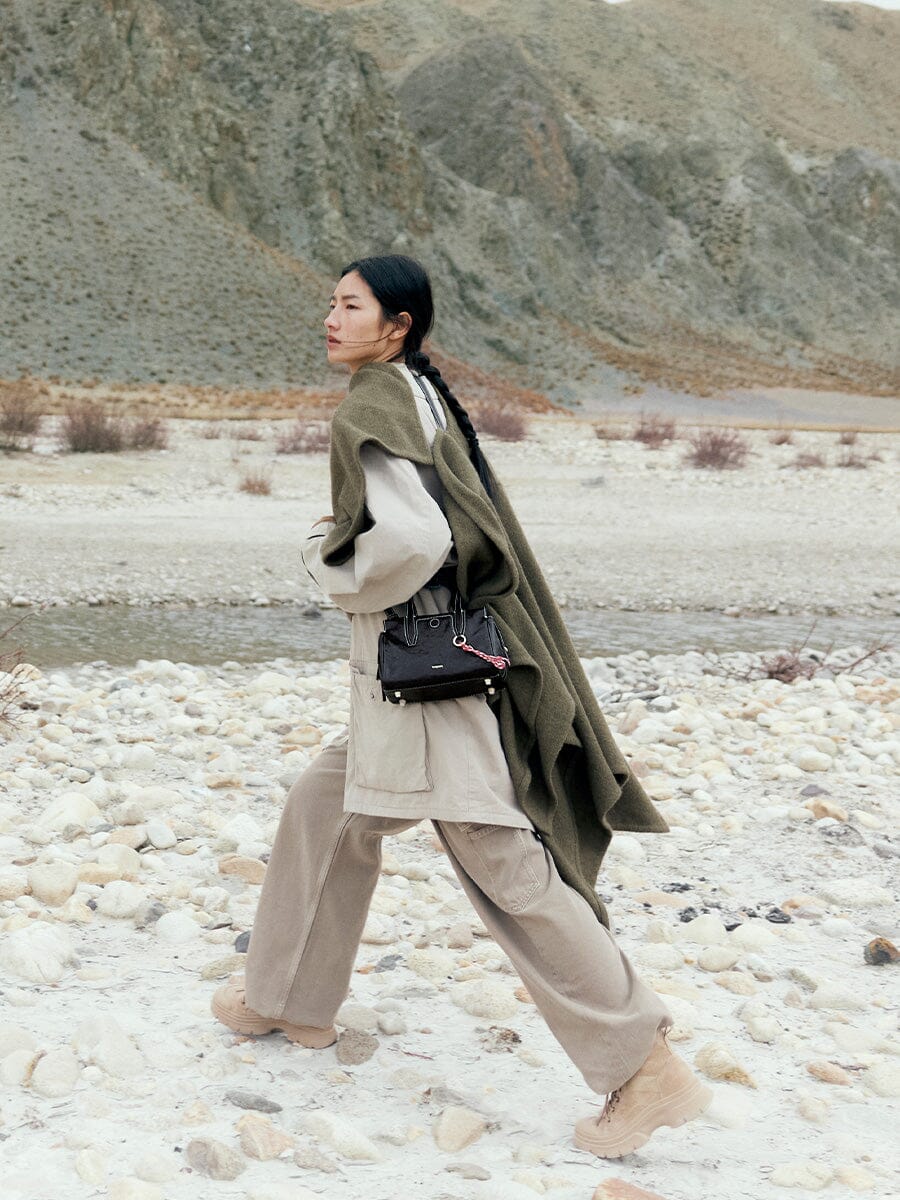 Songmont Mini Yore Duffle Bag Onyx - cross-body on a model walking a rocky landscape