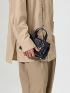 Songmont Mini Yore Duffle Bag Onyx - carried in hand with a tan shirt