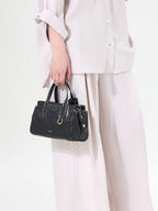 Songmont Mini Yore Duffle Bag Onyx - carried by the top handles in a cream outfit