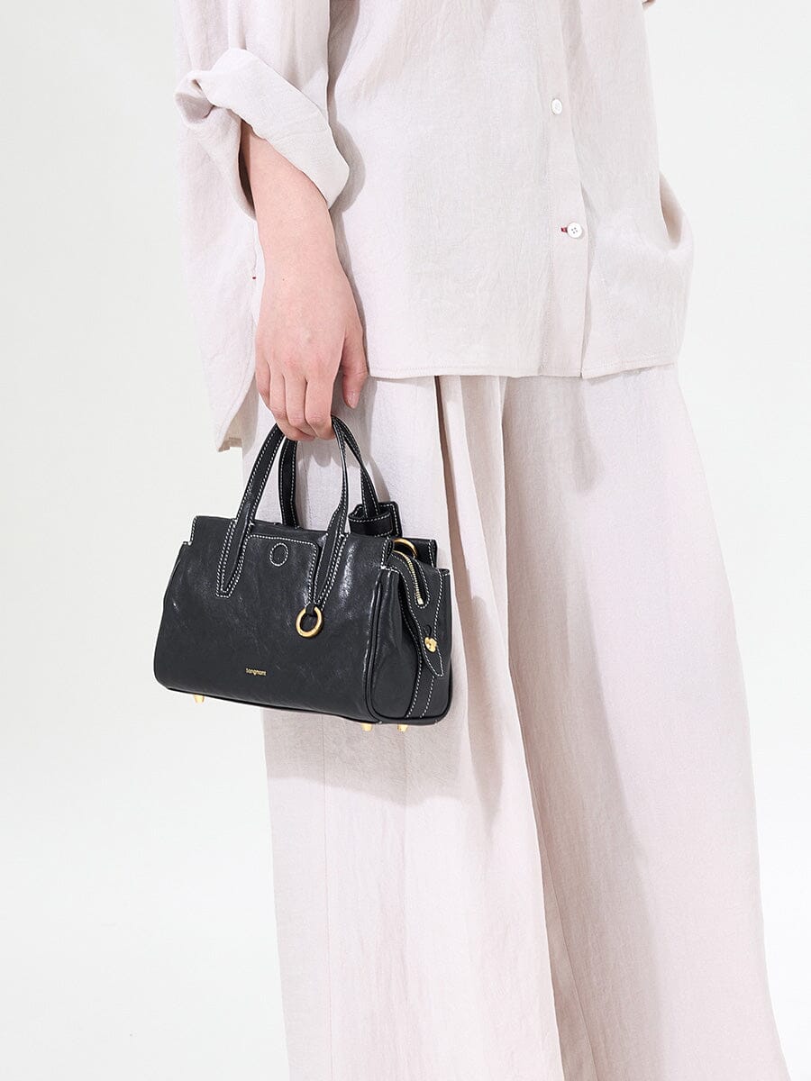 Songmont Mini Yore Duffle Bag Onyx - carried by the top handles in a cream outfit