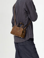 Songmont Mini Yore Duffle Bag Sandal - cross-body strap worn over a grey shirt