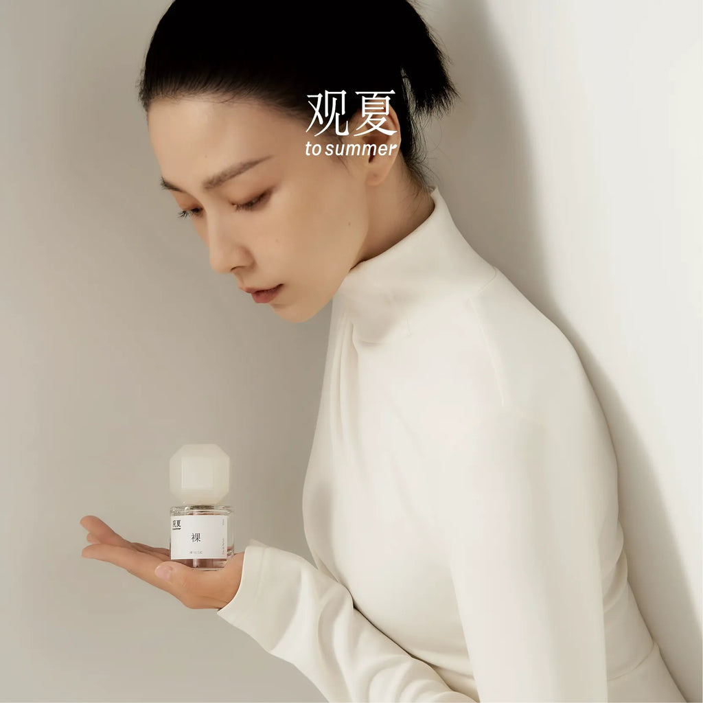 TO SUMMER Nude Eau de Parfum in hand, white turtleneck styling