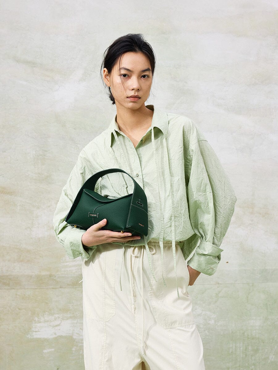 Songmont Small Drippy Roof Bag Emerald - held at the waist with a pale green shirt