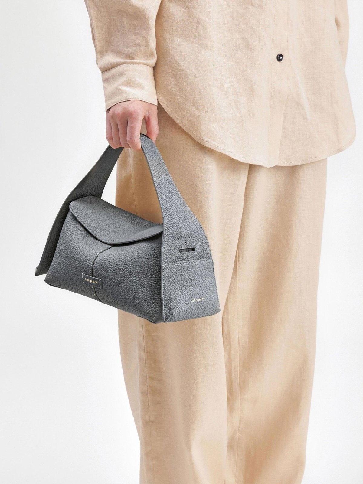 Songmont Small Drippy Roof Bag Stardust - carried by the handle with a cream linen outfit