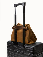 Songmont Small Gather Bag Ochre Suede - on a suitcase handle