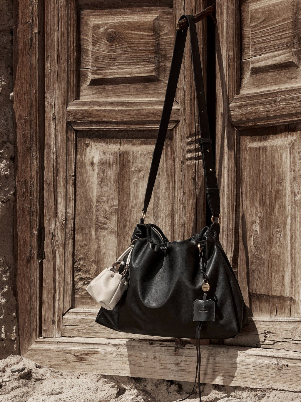 Songmont Small Gather Bag Onyx hanging on a wooden door