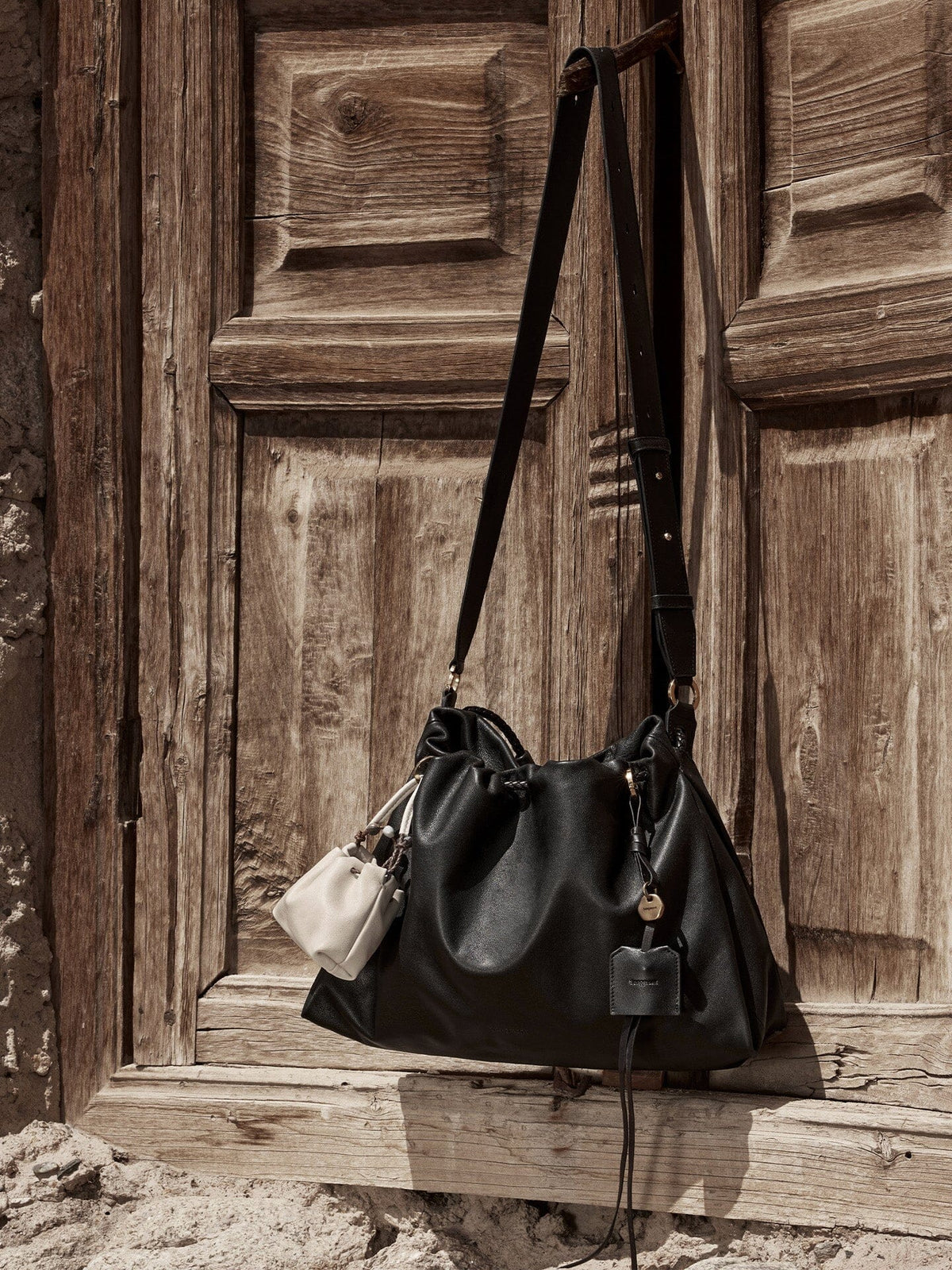 Songmont Small Gather Bag Onyx hanging on a wooden door